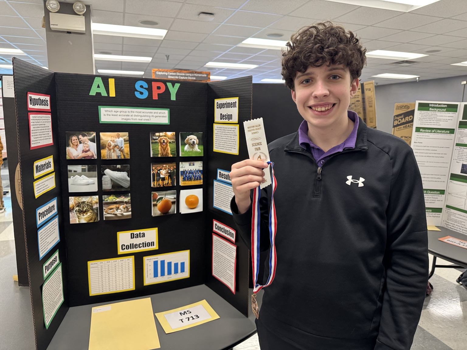 Noah holding a science fair ribbon beside his AI Spy research display